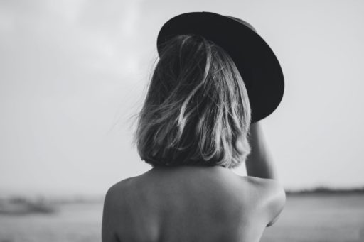 grayscale photography woman holding hat
